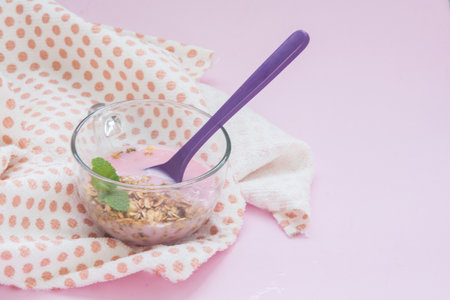 Healthy breakfast. Oat granola with yogurt in glass on pink backgroundの写真素材