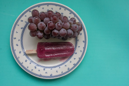 Grapes and ice cream on a plate on a green backgroundの写真素材