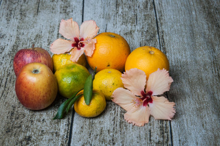 Variety of fruits including apples, oranges, and hibiscus flowersの写真素材