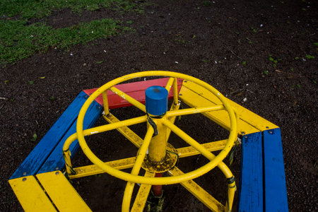 Playground in the park with a yellow and blue wagon wheel.