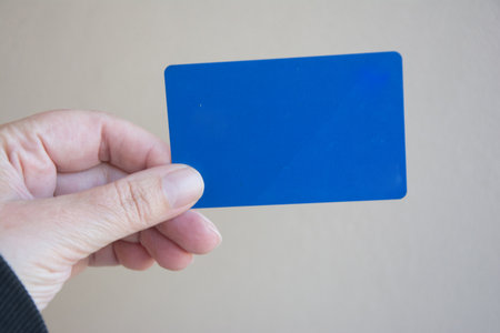 Hand holding a blank blue business card with copy space on white background