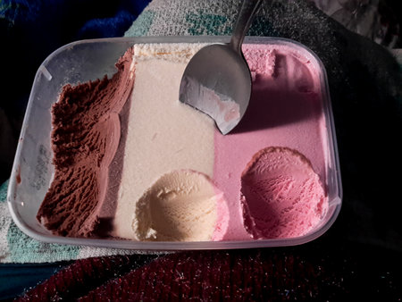 ice cream in a plastic container with spoon, closeup of photo