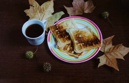 Coffee and waffle on a wooden background with leaves.の写真素材