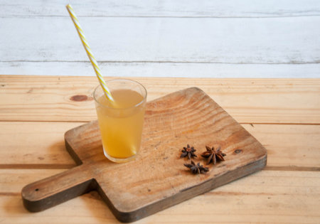 A glass of tepache with a straw on a wooden background.の写真素材