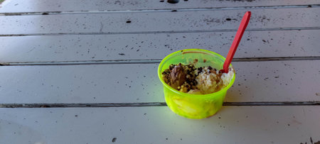 ice cream in plastic cup with red straw on the white table.