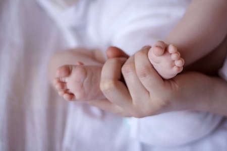 Baby's small little foot in mother's hands.の写真素材