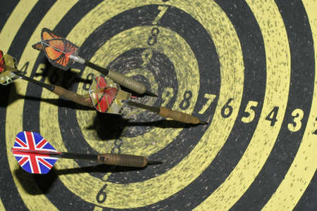 Close-up of a dartboard with four darts inside.