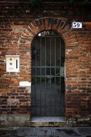Venetian metal door at the brick facade in Venice