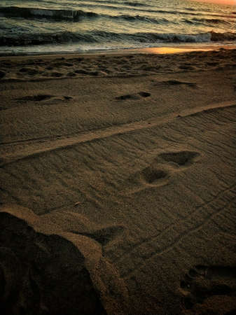footprints on the sand by the sea at sunset