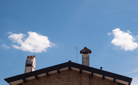 Clouds and blue sky over roof with chimneys.の写真素材