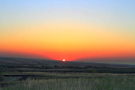colorful sundown sun in steppe by springtimeの写真素材