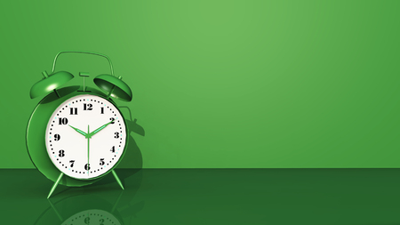 Green alarm clock against a green backgroundの写真素材