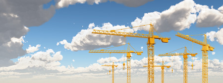 Construction cranes against a blue sky with cloudsの写真素材
