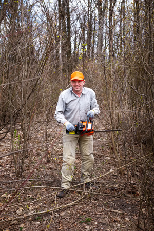 Lumberjack logger worker cutting firewood timber tree in forest with chainsawの写真素材