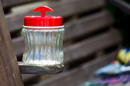 Empty jar whith red plastic cover on a  wooden boardの写真素材