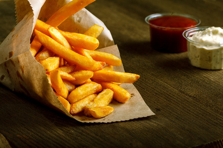 Fresh fried french fries with ketchup and white sauce on wooden backgroundの写真素材