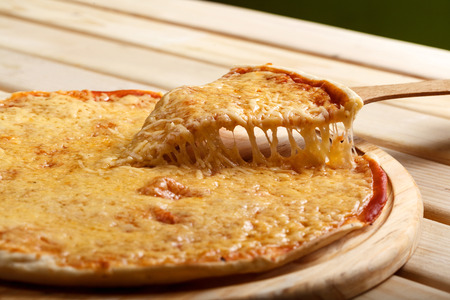 Slice of pizza margarita lifted up on a boardの写真素材