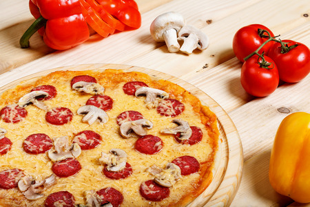 Delicious hot italian pizzas served on wooden table with tomato, mushrooms, garlic and pepperの写真素材