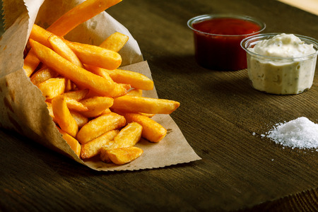 Fresh fried french fries with ketchup and white sauce on wooden backgroundの写真素材