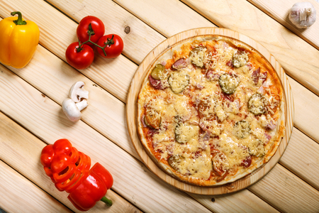 Delicious hot italian pizzas served on wooden table with tomato, mushrooms, garlic and pepperの写真素材