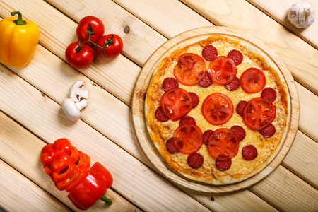 Delicious hot italian pizzas served on wooden table with tomato, mushrooms, garlic and pepperの写真素材