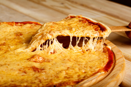 Slice of pizza margarita lifted up on a boardの写真素材