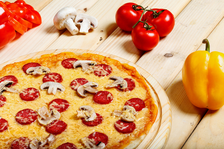 Delicious hot italian pizzas served on wooden table with tomato, mushrooms, garlic and pepperの写真素材