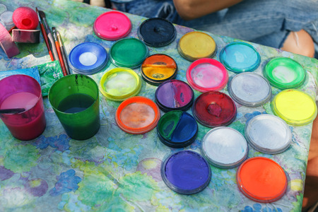 Water paints and paint brush. Watercolor bottle color stains on tableの写真素材