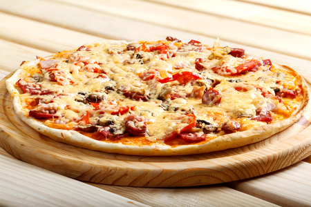 Delicious hot italian pizzas served on wooden table with tomato, mushrooms, garlic and pepperの写真素材