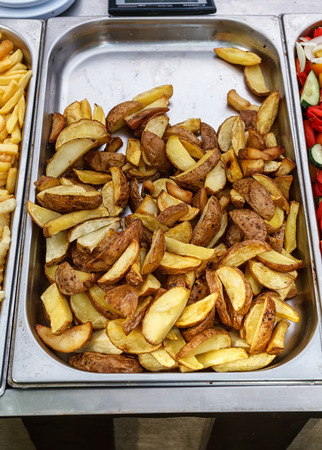Steel container with roasted potato wedges, village style potatoesの写真素材