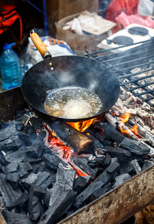 old chinese wok pan with boiling oil on a coal grillの写真素材