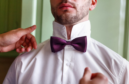 The groom in a white collar fixing his bow tieの写真素材