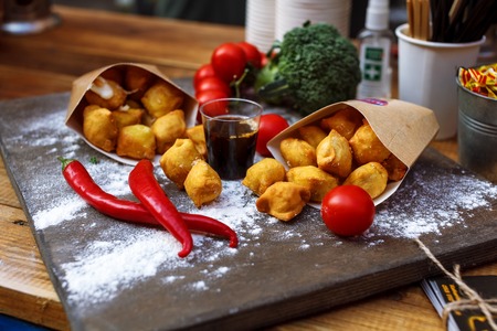 Breaded potato croquettes with tomato on a wooden table close-up