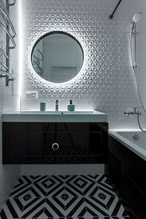 A modern bathroom with a black vanity, mirror, and hardware.の写真素材