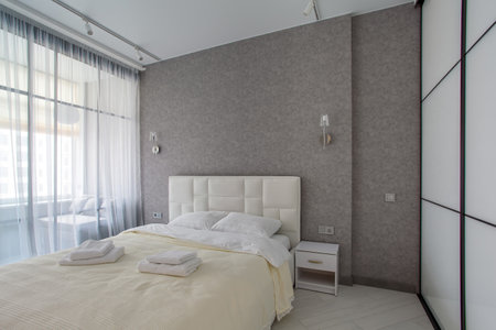 Master bedroom with sliding wardrobe and balcony door. Elegant and comfortable hotel bedroom interiorの写真素材