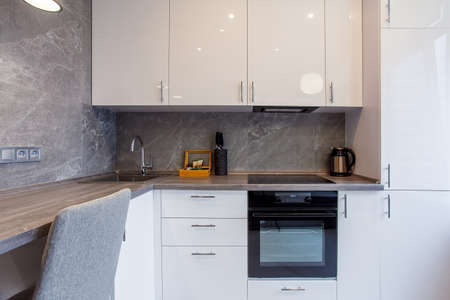 Clean kitchen in a small cozy contemporary studio apartment. Table and chairs in the foreground. Built in household applianceの写真素材