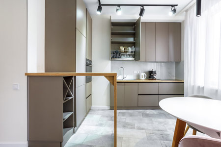 Modern kitchen in a small cozy contemporary studio apartment. Table and chairs in the foreground. Built in household applianceの写真素材