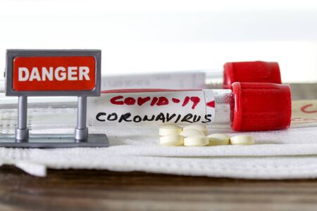 Coronavirus alias COVID -19 on blood tube with pills and danger sign