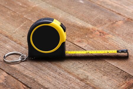 Yellow and black measure tape on wooden table