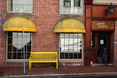 NEW CANAAN, CT, USA - OCTOBER 4, 2020: Green & tonic storefront with yellow seat bench on Burtis Avenue in downtownのeditorial素材