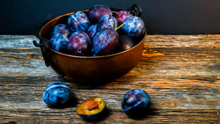 Italian plums inside  rustic looking bowl and  wooden table