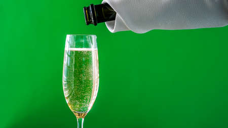 Glass with sparkling wine with bottle and green background close upの写真素材