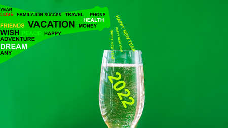 Happy New Year with wishes and wine glass with bubbles on green backgroundの写真素材