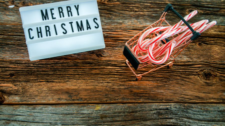 Push cart with Christmas candy and lightbox with wish on rustic table from aboveの写真素材