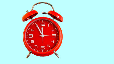 Red alarm clock isolated on light blue colored backgroundの写真素材