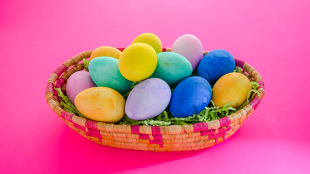 Colorful Easter eggs inside basket  on pink backgroundの写真素材