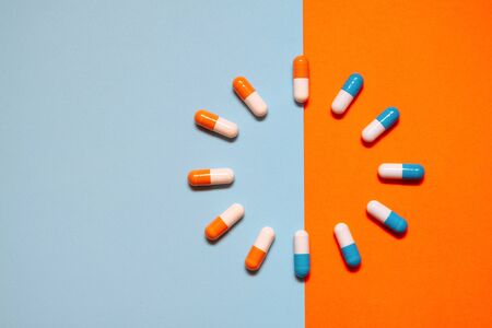 Blue and orange vitamins on a blue-orange backgroundの写真素材