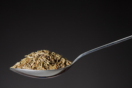spoon with pile of cumin grain on black backgroundの写真素材