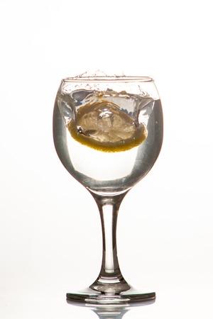 Glass glass of water with lemon on the isolated background. Mountain mineral pure mountain water with gas bubbles and a lemon slice and spray tonic refreshing sports drink.の写真素材