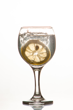 Glass glass of water with lemon on the isolated background. Mountain mineral pure mountain water with gas bubbles and a lemon slice and spray tonic refreshing sports drink.の写真素材